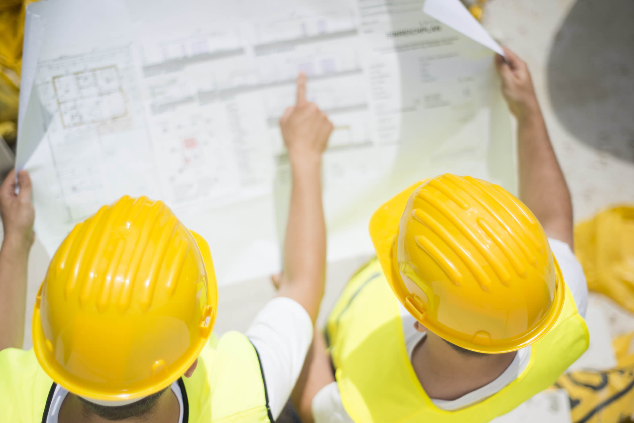 Two construction workers looking at a blueprint and pointing