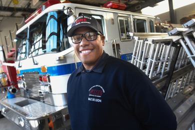 A student smiling in front of a fire engine.