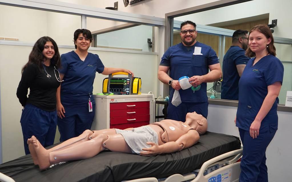 Crafton Hills College respiratory care students gathered around a patient simulator mannequin in a simulation room.